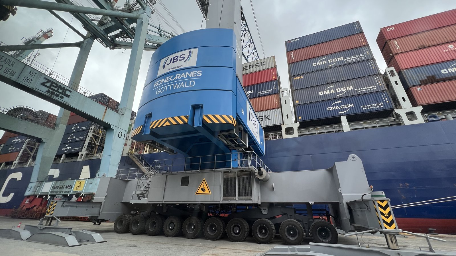 Gru portuale mobile blu in funzione accanto a una nave portacontainer